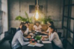 Young business people are discussing together a new startup project. A glowing light bulb as a new idea.